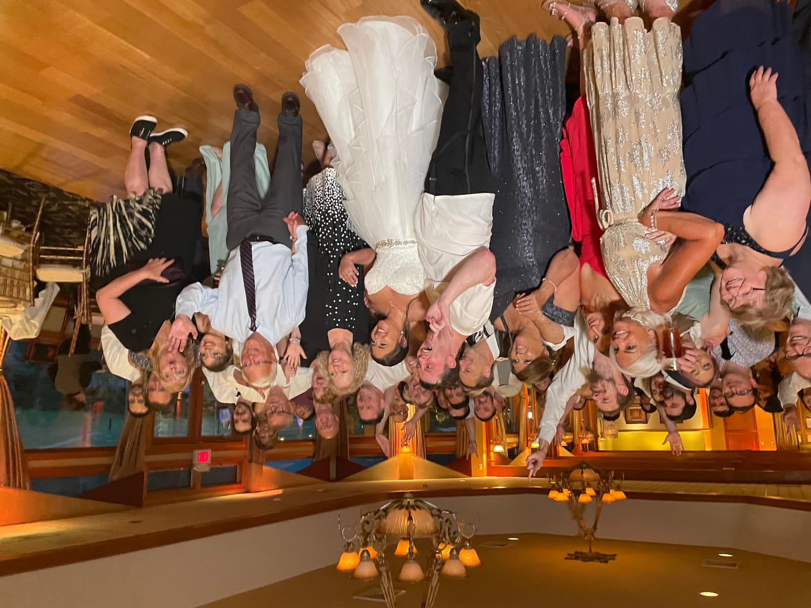 Full wedding group portrait outside the windowed reception space at Black Bear Golf Club
