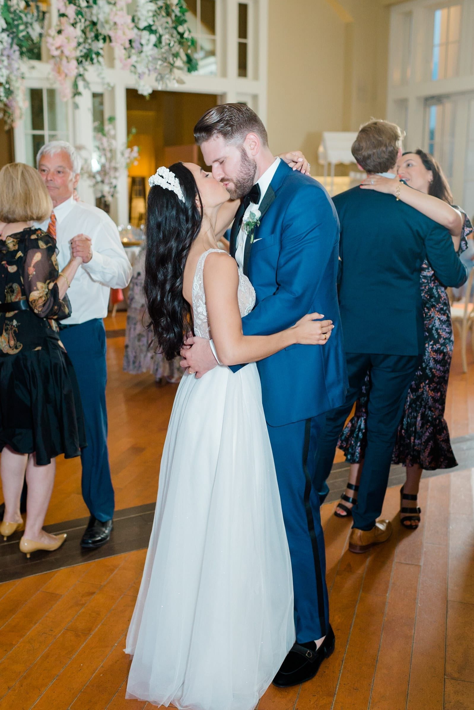 Bride and groom sharing a kiss on the dance floor surrounded by guests