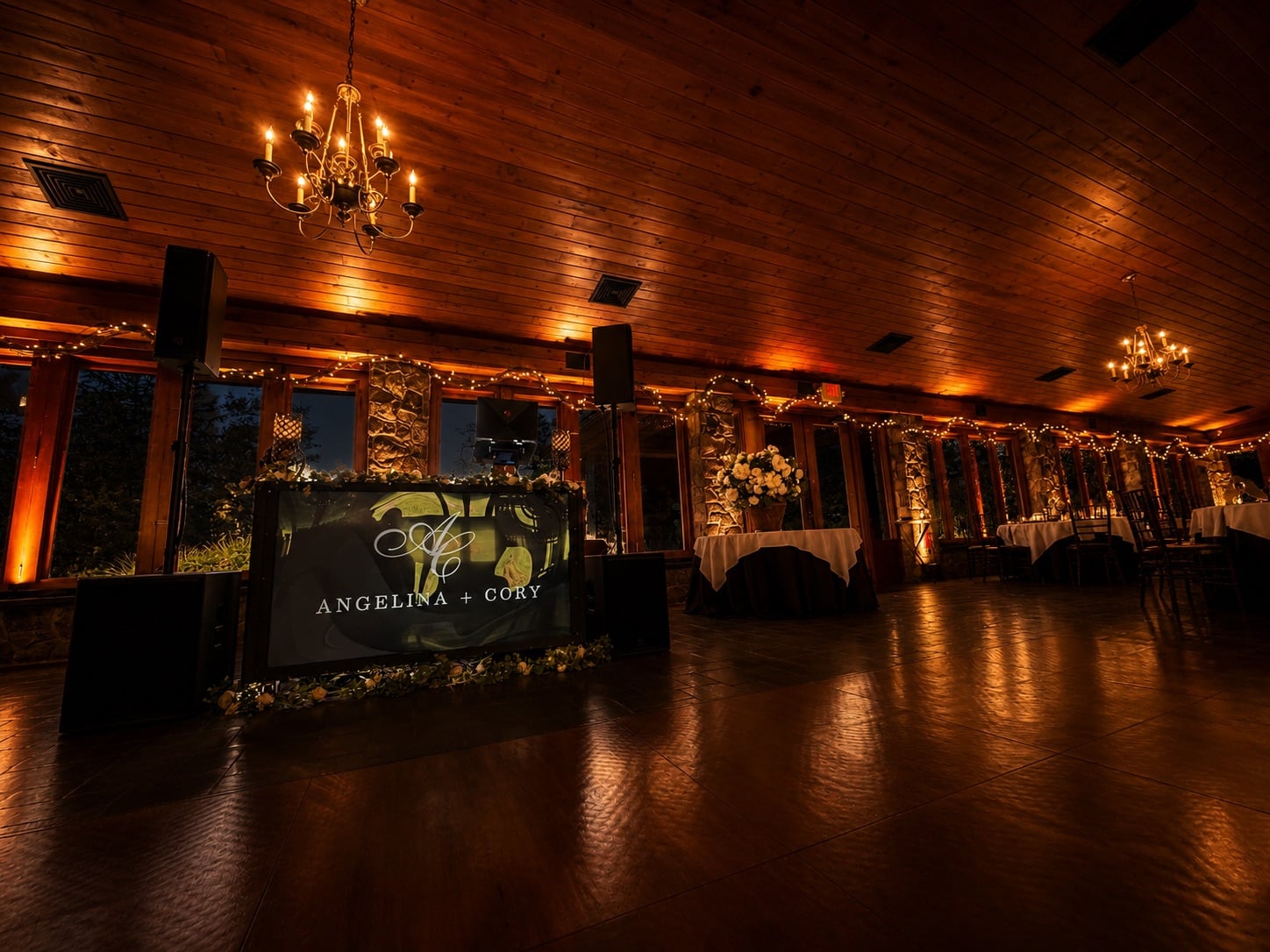 Lawnhaven at Stroudsmoor by Wedgewood Weddings — Angelina + Cory DJ booth view with warm amber uplighting along the windows and string-lit interior at night